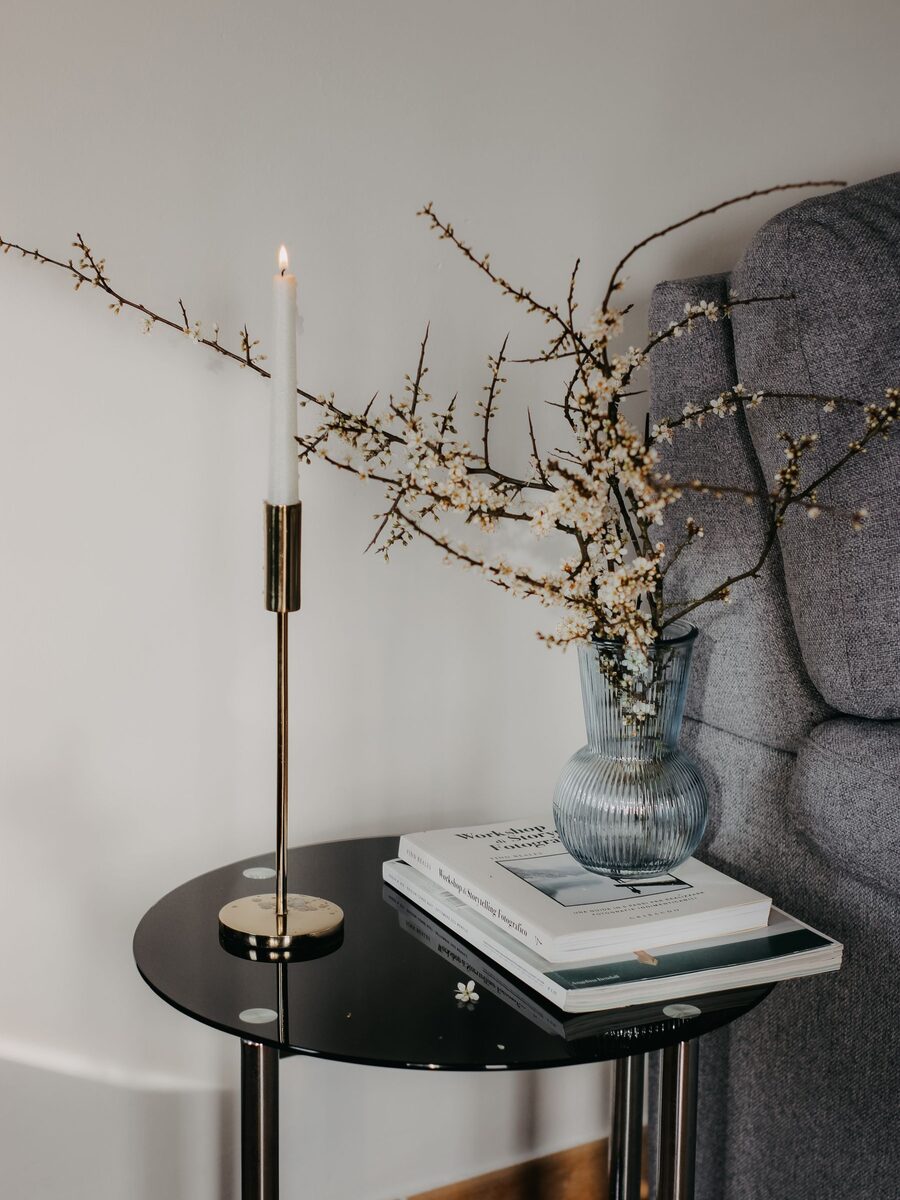 Black side table styled with a stone vase, dried branches and a brass candlestick