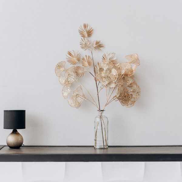 Slim console table with a small shaded lamp and dried botanical stems