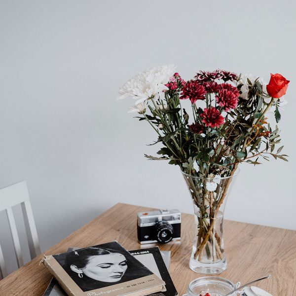 Solid timber table styled with a glass vase of flowers and a stack of books